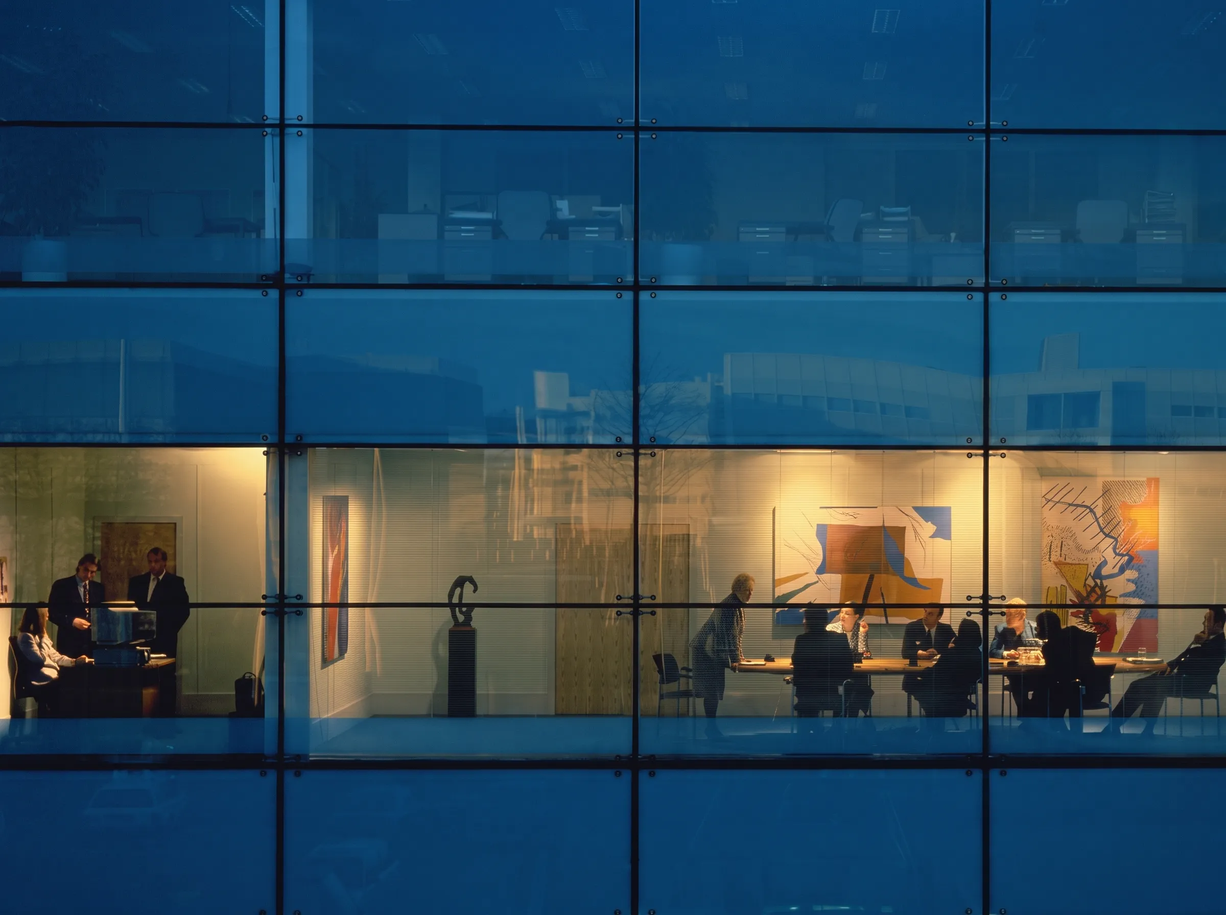 Corporate office building lit up at dusk with employees working